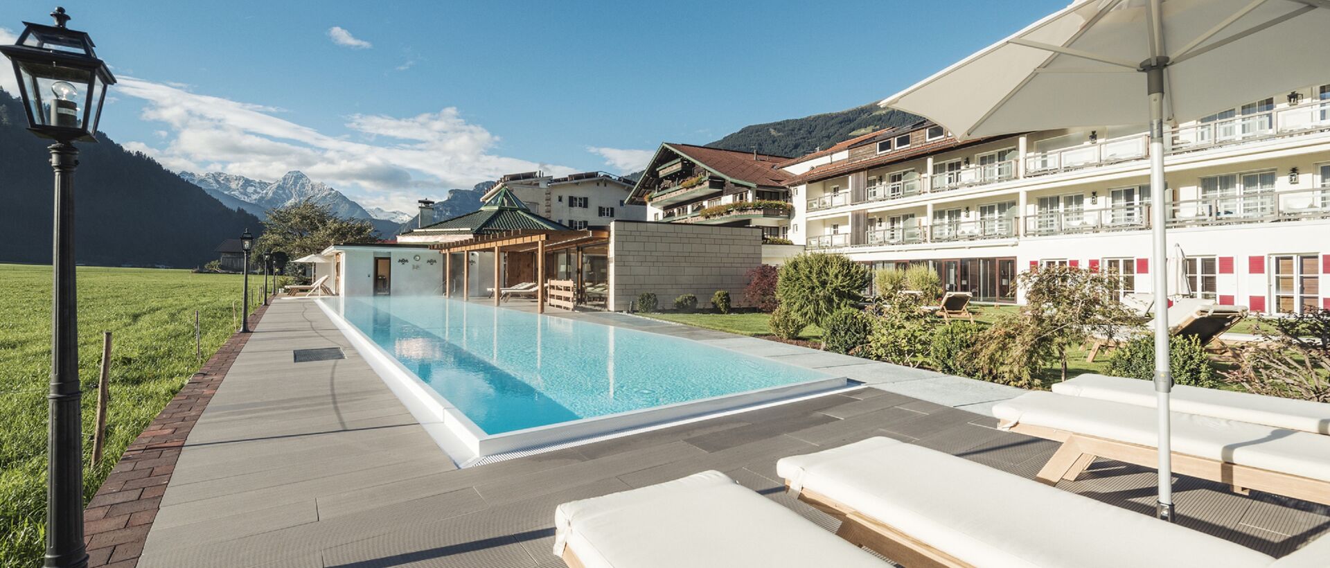 Pool vor Hotelanlage mit Liegen und Bergblick