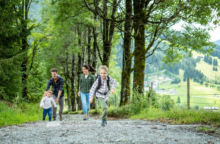 Family walking down a rocky path, child running ahead