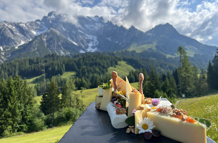 A selection of regional cheese specialties set against an impressive mountain backdrop.