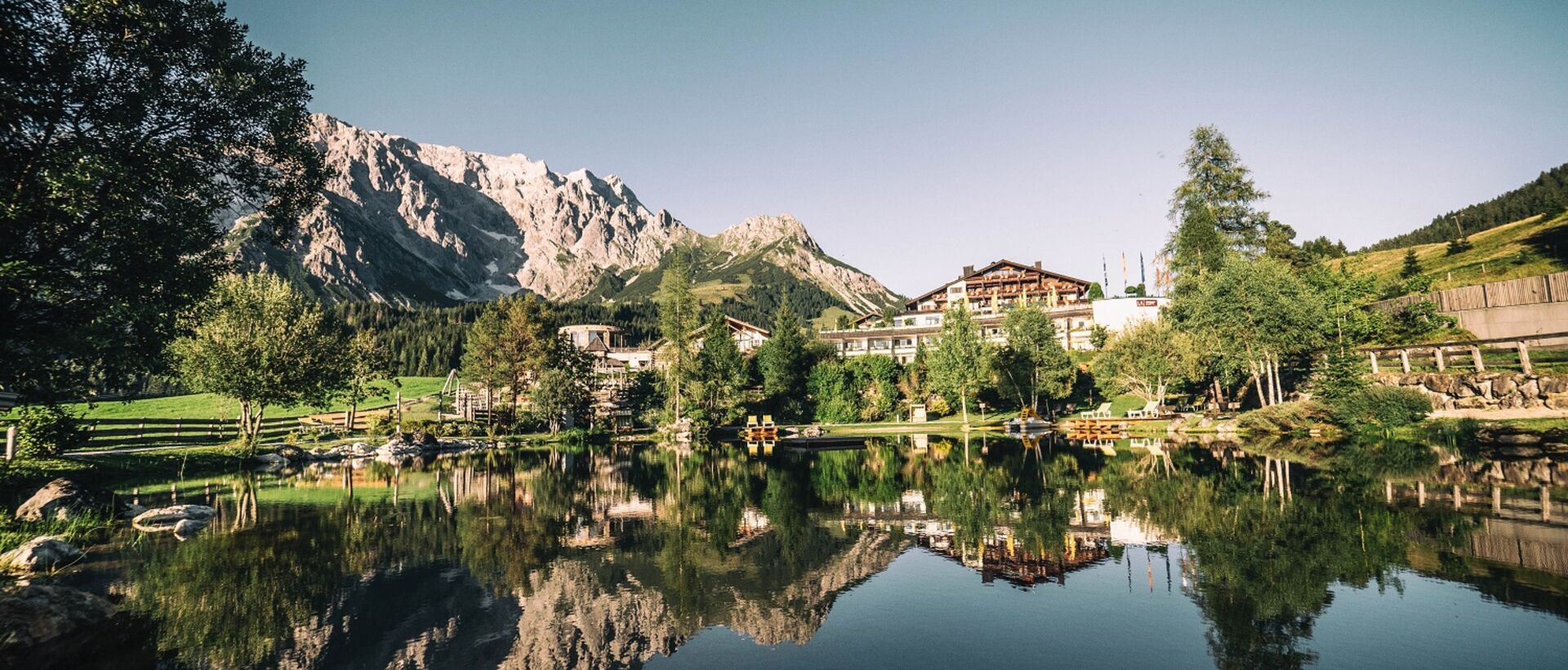 Mountain lake with reflections of mountains and hotel complex in the clear water