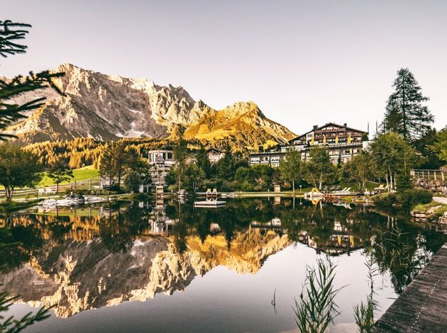 Bergsee mit Spiegelung von Bergen und Gebäuden im Wasser