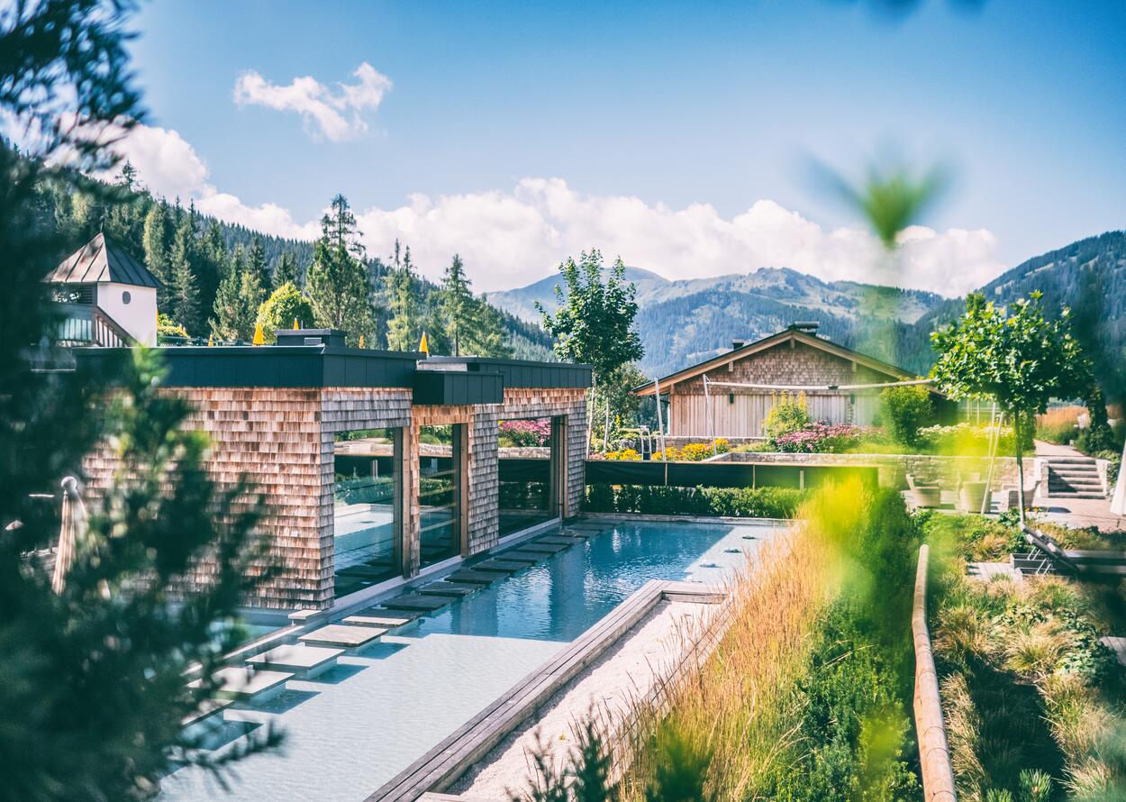 Außenpool und Gartenanlage mit Blick auf die umliegende Berglandschaft.