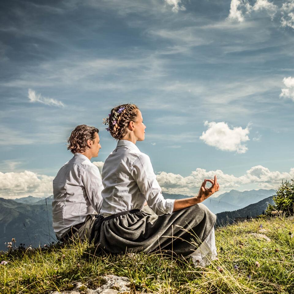 Paar auf der Wiese im Schneidersitz Yoga | Wellneshotel Alpenrose, Österreich