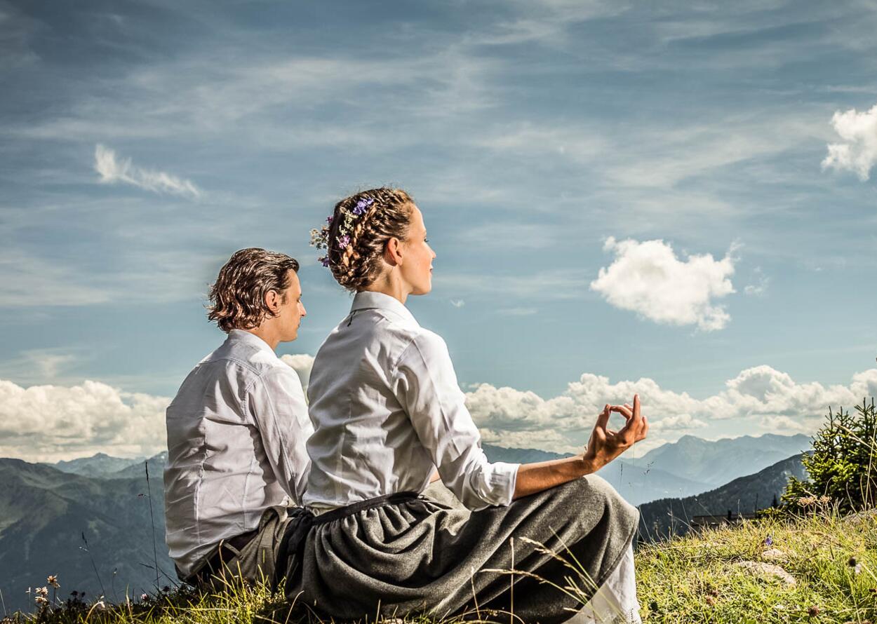 Paar auf der Wiese im Schneidersitz Yoga | Wellneshotel Alpenrose, Österreich