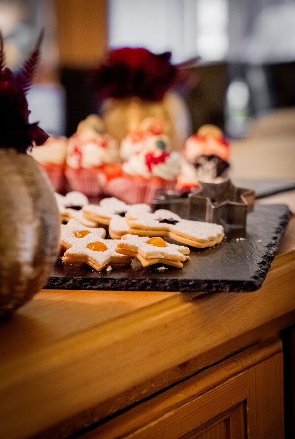 Star-shaped cookies with jam and muffins on a dark serving tray