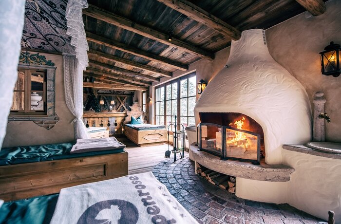 Gemütlicher Ruheraum mit Kamin, Holzbalkendecke und Bett mit Alpenrose-Handtuch