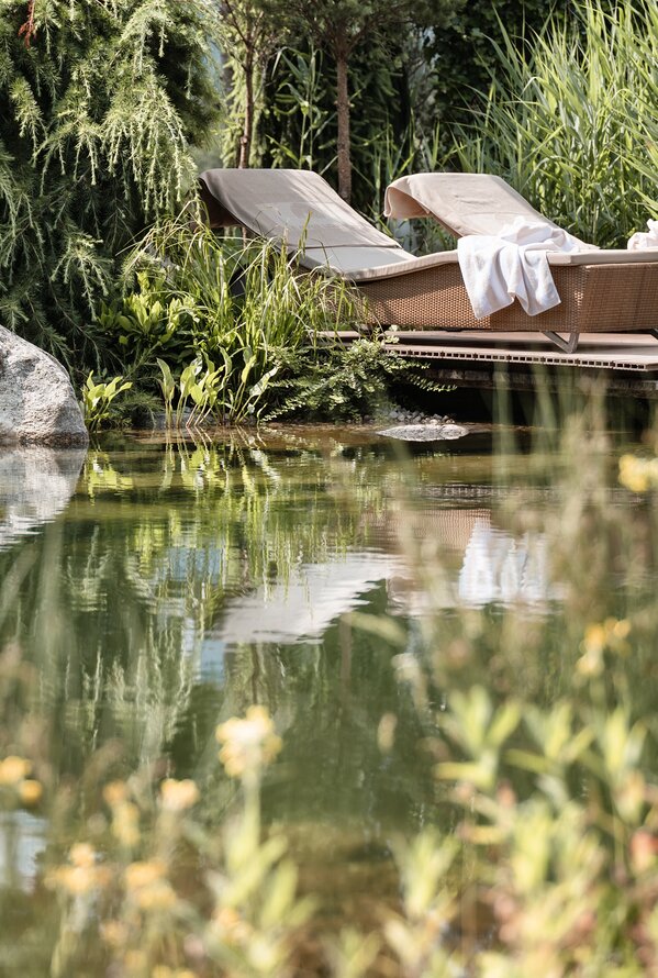 Ruhiger Rückzugsort am Naturteich mit Liegen, Schilf und entspannter Spa-Atmosphäre