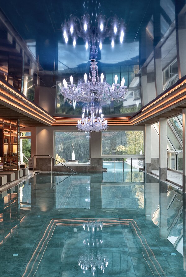 Luxuriöser Indoor-Pool mit Kronleuchtern, modernem Design und exklusiver Wellnessatmosphäre