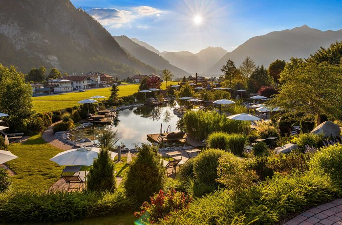 Weitläufige Garten- und Naturteichlandschaft mit alpinem Panorama in der Abendsonne