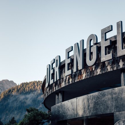 Außenansicht Hotel "Der Engel" mit großem Schriftzug vor Bergkulisse