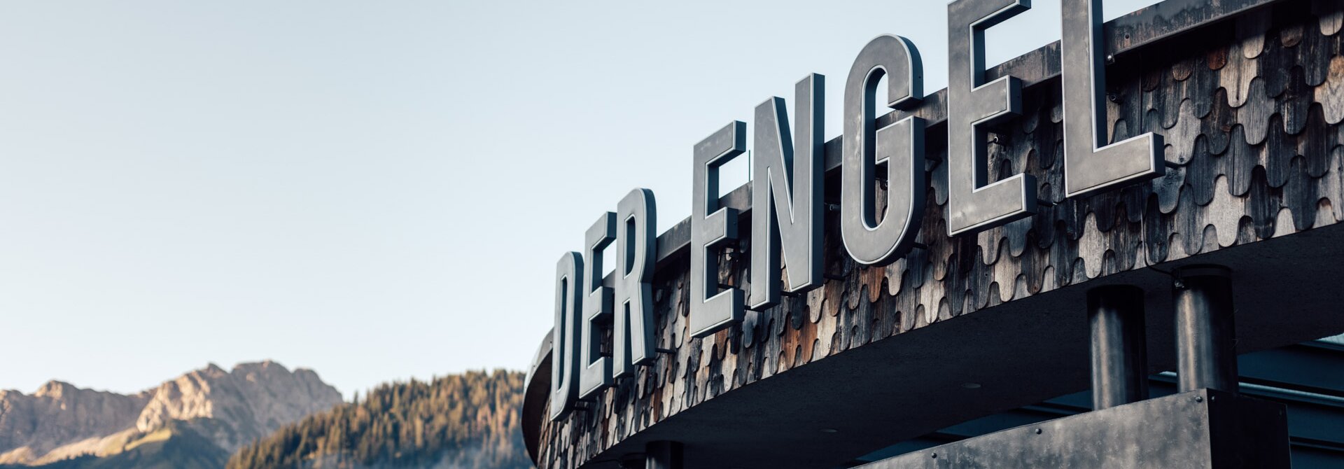 Außenansicht Hotel "Der Engel" mit großem Schriftzug vor Bergkulisse