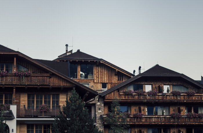 Holzhäuser mit dunklen Dächern vor grauem Himmel