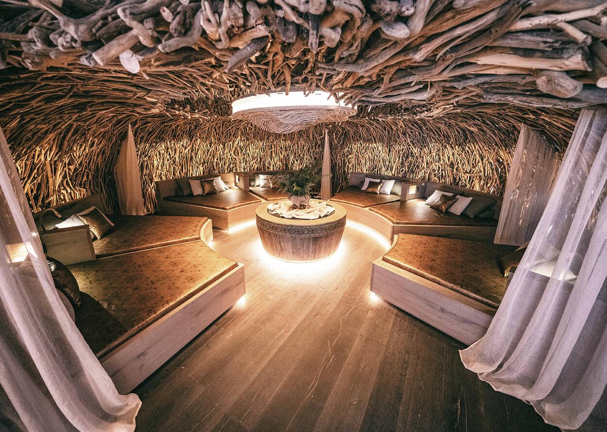Spa room with loungers around a round table, ceiling decorated with branches and roots
