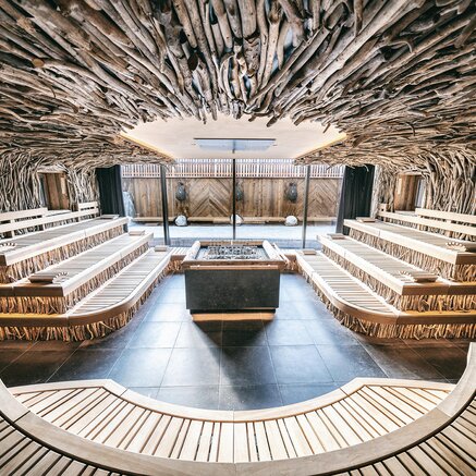 Interior view of a spa area with wooden benches and a ceiling made of branches