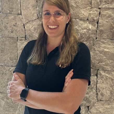 Frau mit Brille lächelt vor einer Steinwand