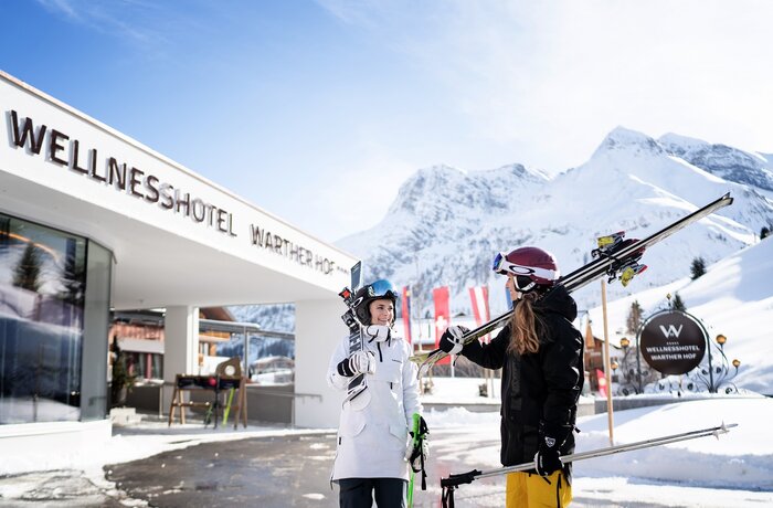 Zwei Skifahrerinnen vor dem Hotel Warther Hof im Schnee