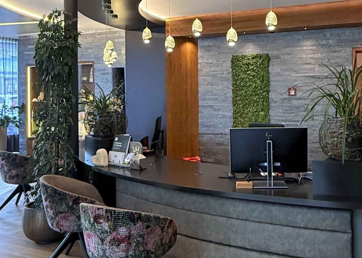 Modern hotel reception area with stylish decor, plants, and warm lighting.
