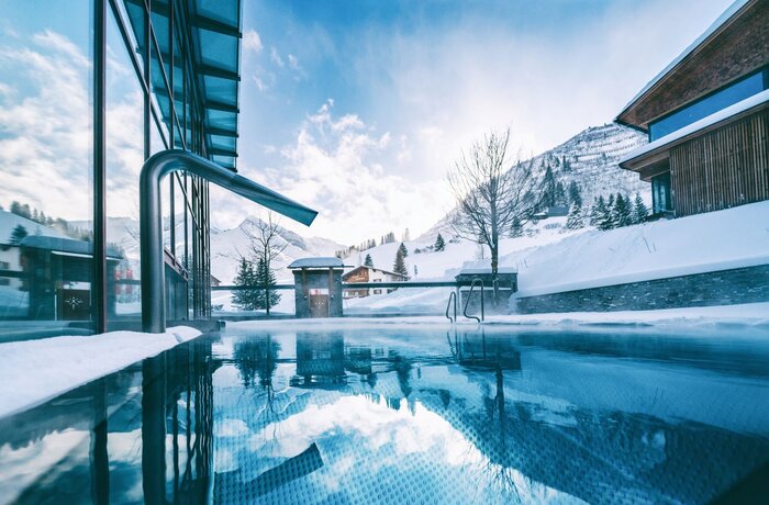 Schwimmbad mit Bergpanorama im Winter unter blauem Himmel