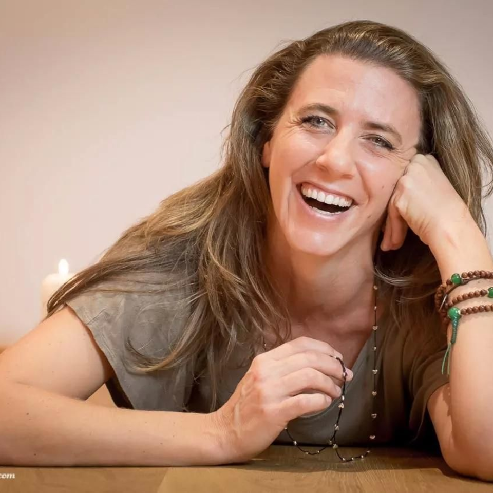 Lachende Frau mit langen Haaren und Schmuck an Tisch