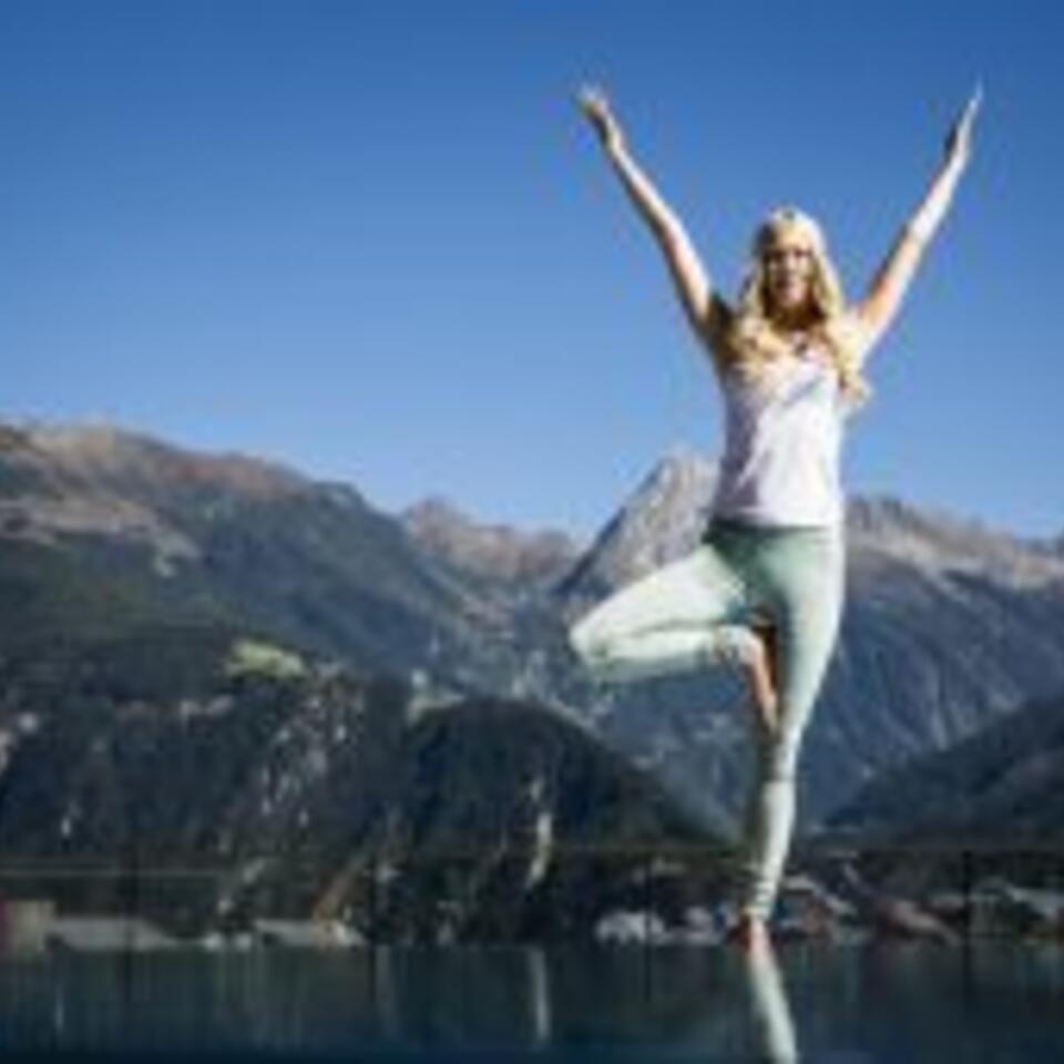 Frau macht Yoga-Baum vor Bergpanorama