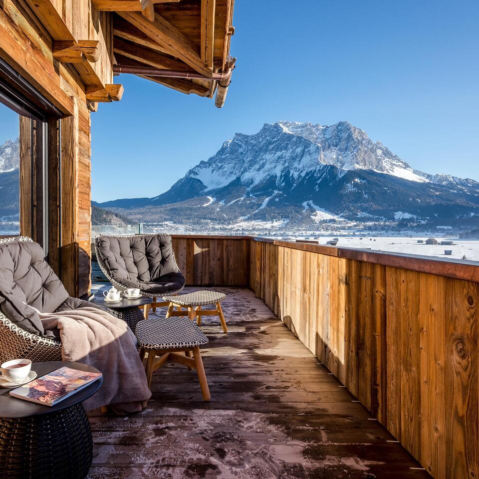 Wooden balcony with seating and view of snow-capped mountain under blue sky