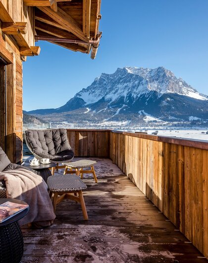 Wooden balcony with seating and view of snow-capped mountain under blue sky