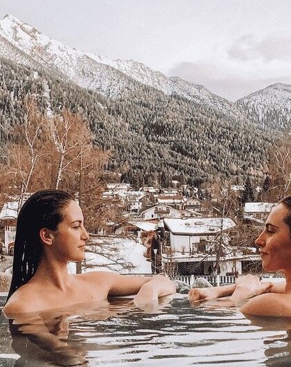 Zwei Frauen im Pool vor verschneiter Berglandschaft