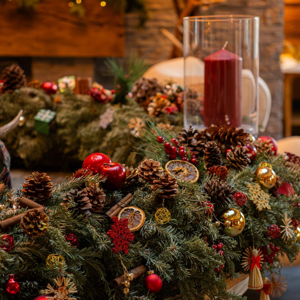 Christmas table decoration with fir branches, candles, cones, orange slices and Christmas tree balls