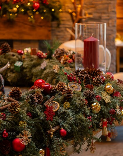 Weihnachtliche Tischdeko mit Tannengrün, Kerze, Zapfen, Orangenscheiben und Christbaumkugeln