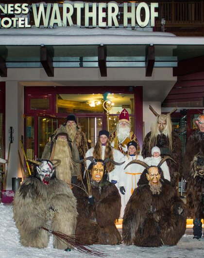 Group of people in costume in front of the Wellness Hotel Warther Hof in the snow