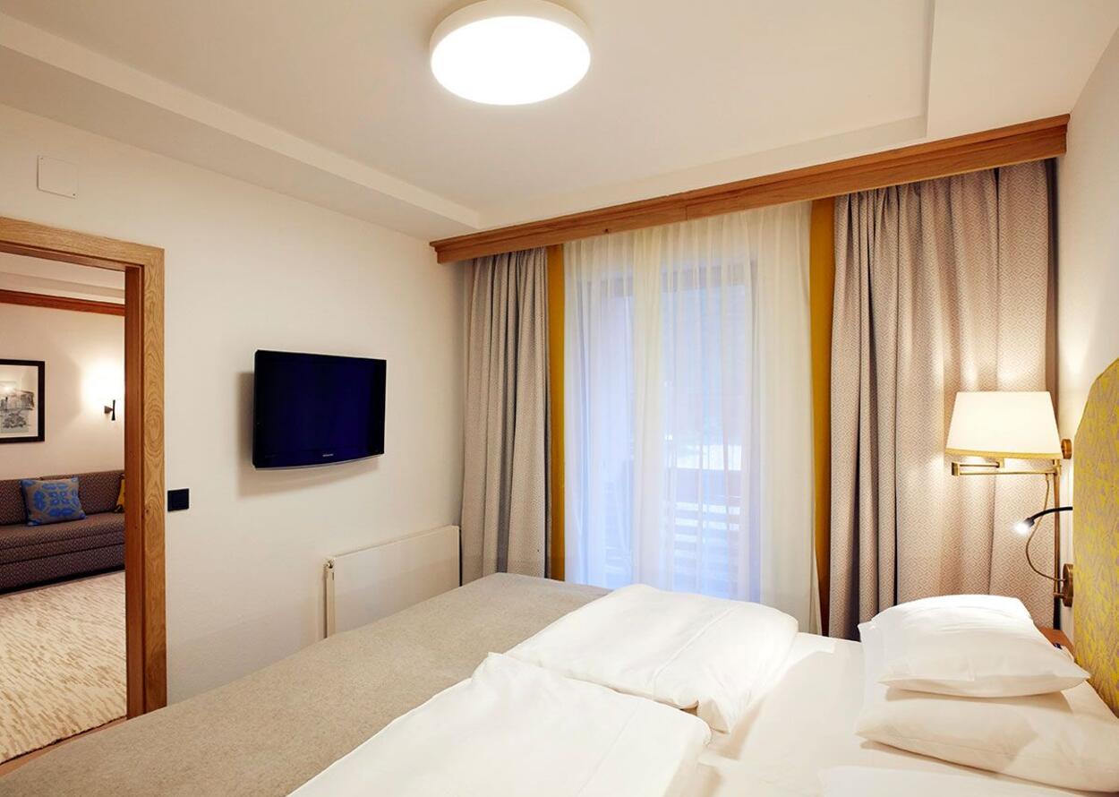 Bedroom with double bed, TV on the wall and curtains in front of the window