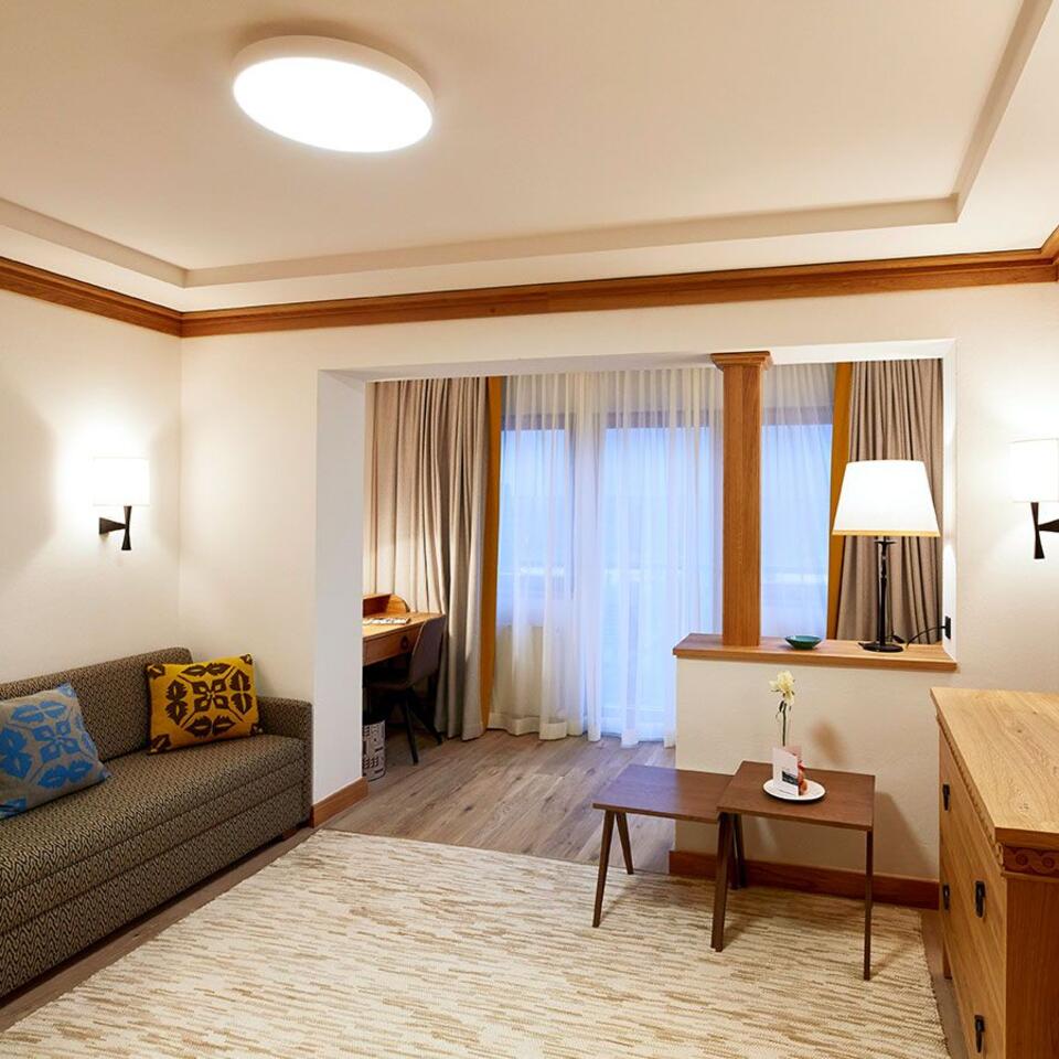 Wohnzimmer mit Sofa, Teppich, Schreibtisch und Vorhängen