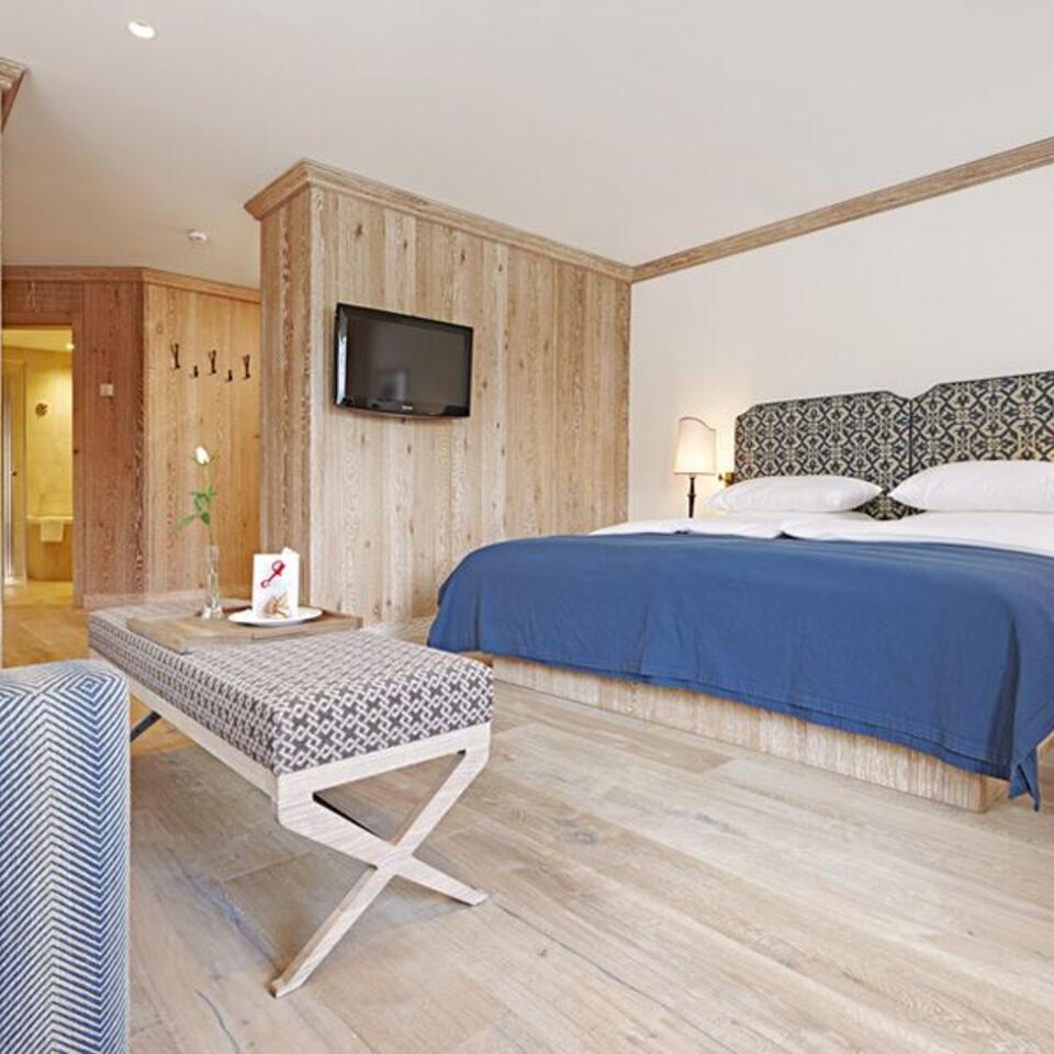 Hotelzimmer mit Doppelbett, Fernseher und Holzwand