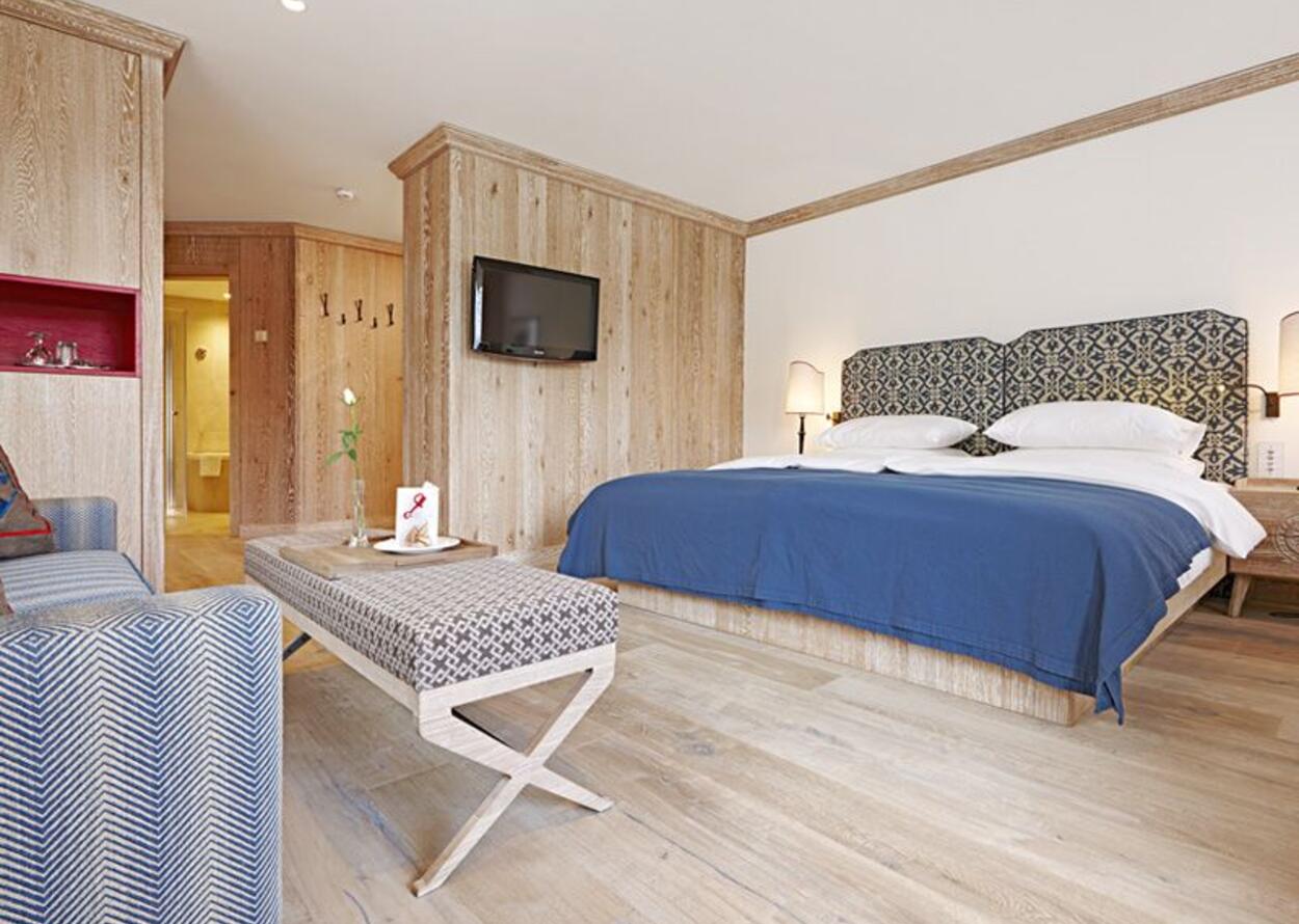 Hotel room with double bed, TV and wooden wall