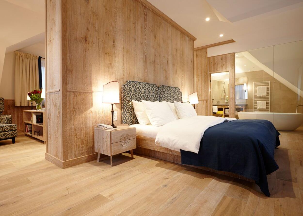 Bedroom with wooden wall, bed, bedside table and adjoining bathroom