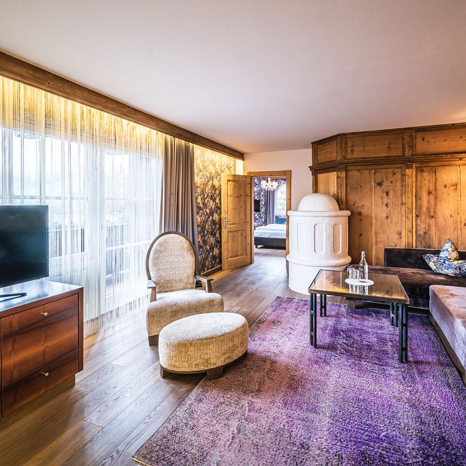 Hotel room with armchair, sofa, carpet, fireplace and wooden wall