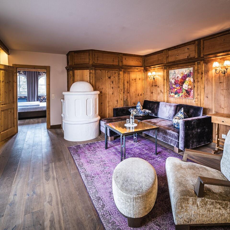 Wood-paneled living room with sofa, armchair, fireplace and purple carpet