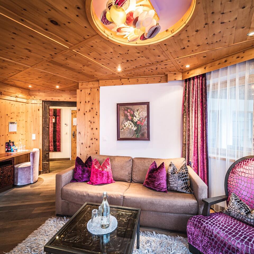 Cozy hotel room with wooden walls, sofa, armchair and eye-catching ceiling lamp