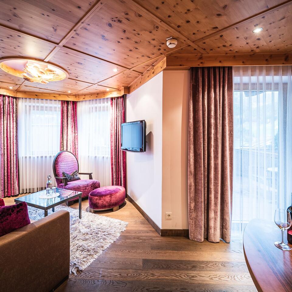 Hotel room with wooden ceiling, armchair, TV and curtains