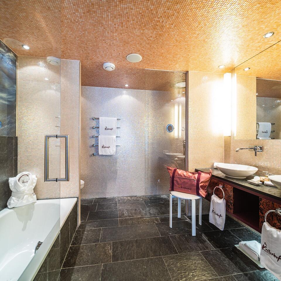 Modern bathroom with bathtub, shower, sink and dark stone floor