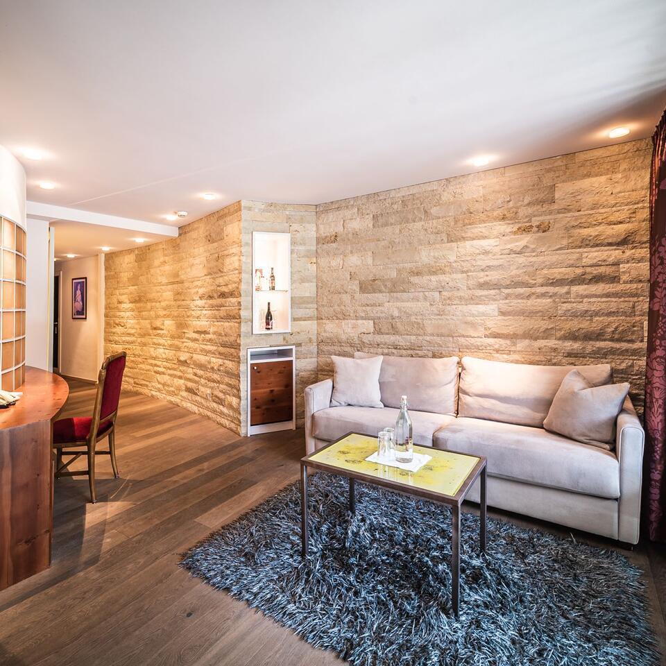 Living room with sofa, table, carpet and stone wall