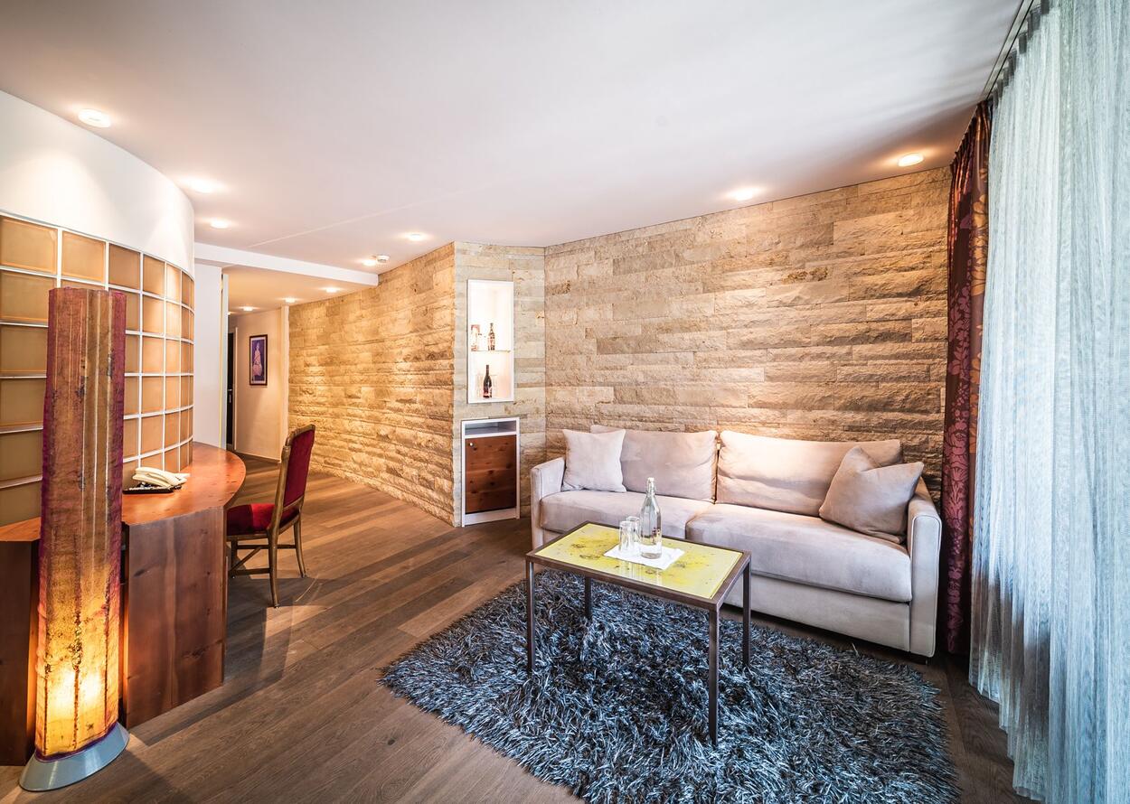Wohnzimmer mit Sofa, Tisch, Teppich und Steinwand