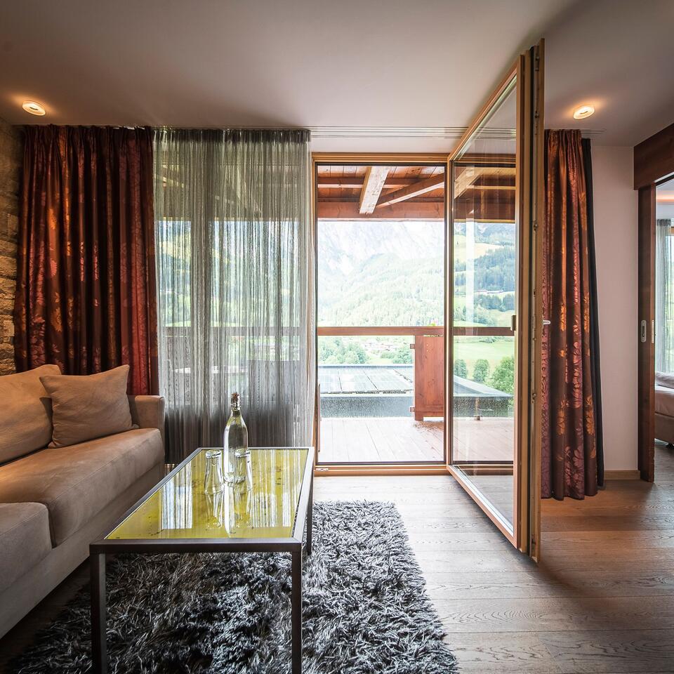 Living room with sofa, carpet, glass table and balcony door with view of nature