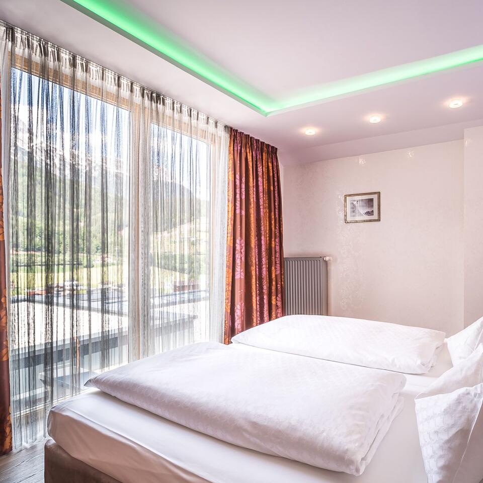 Bedroom with double bed, curtains and mountain view