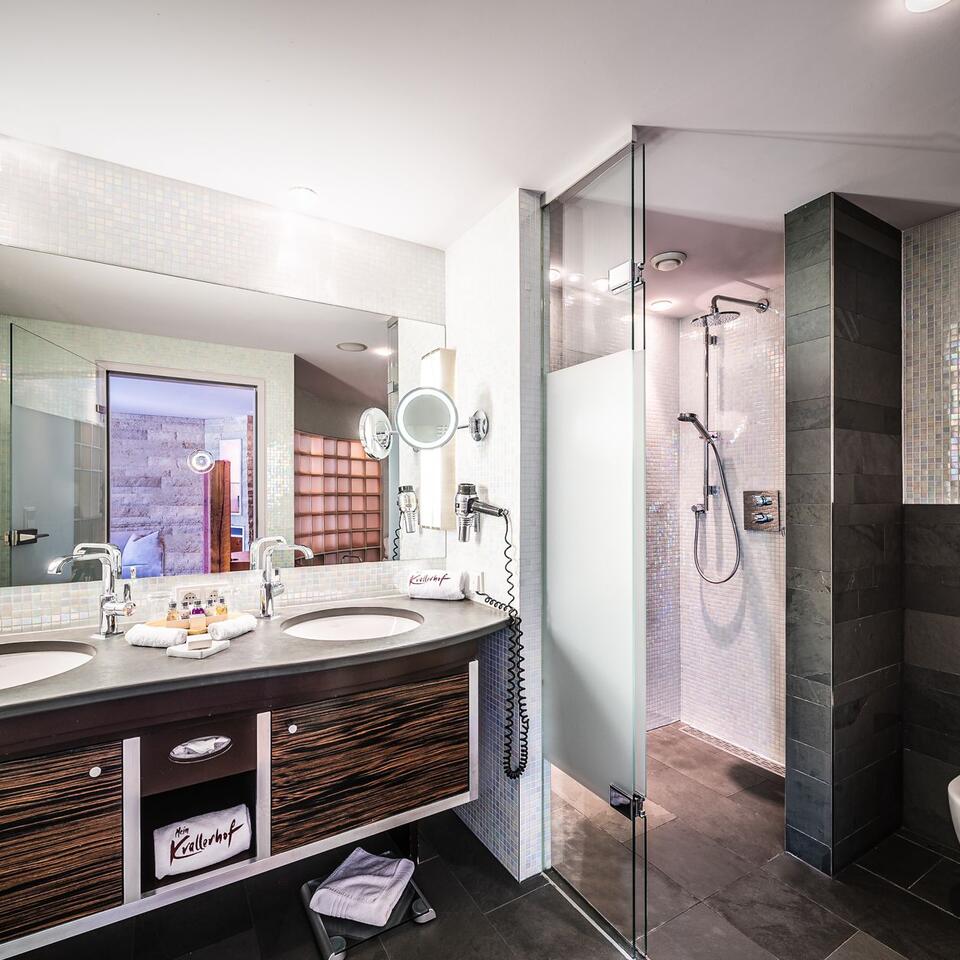 Modern bathroom with double sink, mirror, shower and dark accents