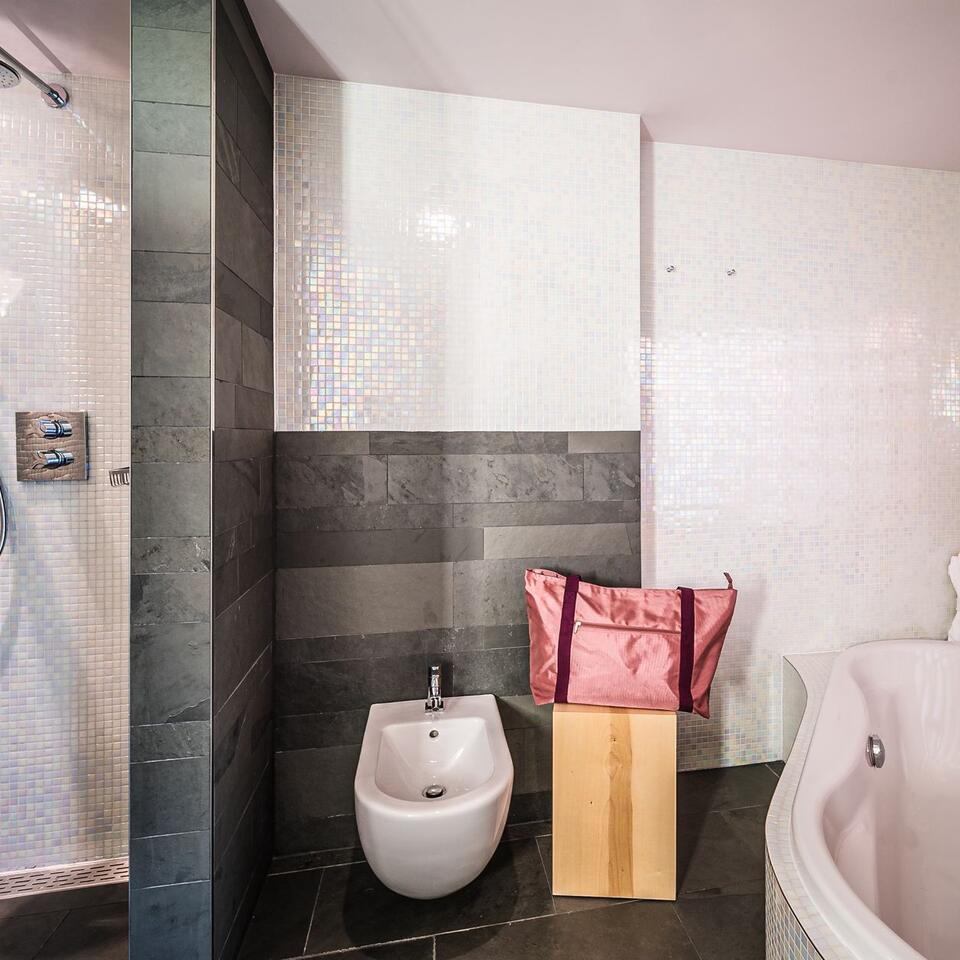 Modern bathroom with bidet, bathtub and pink bag on a stool