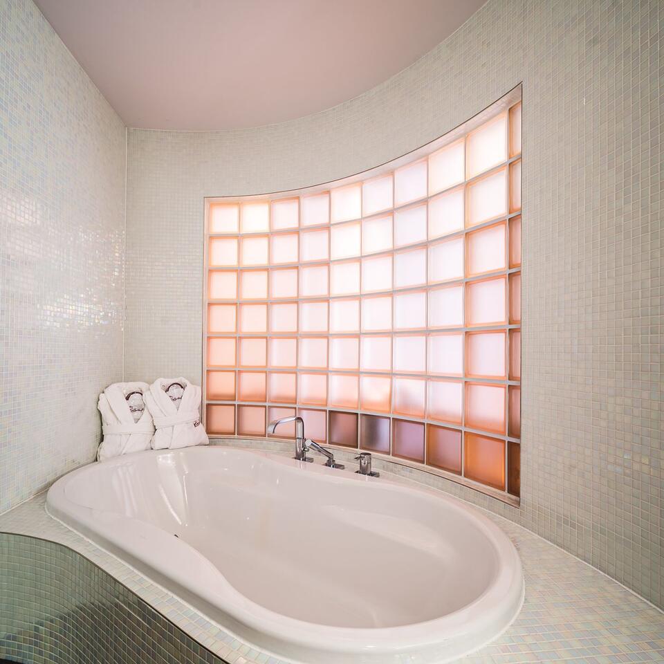 White bathtub in front of glass block window