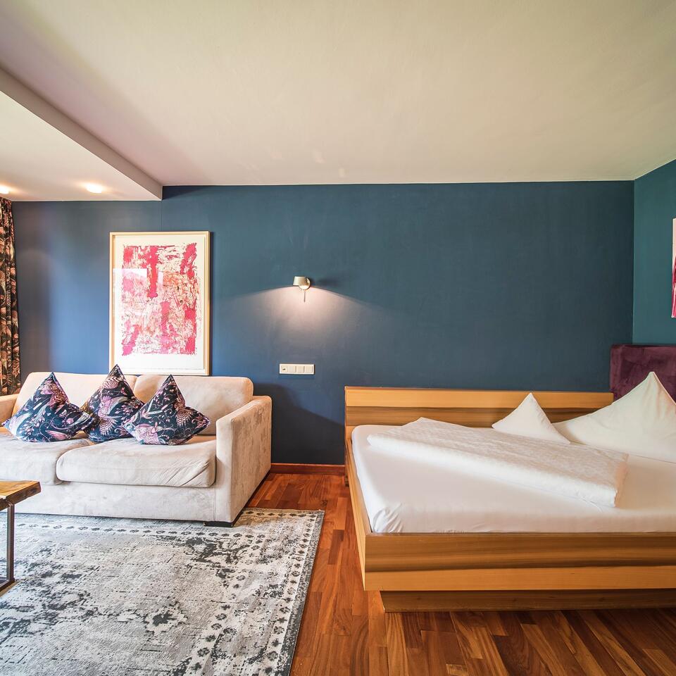 Hotel room with double bed, sofa, carpet and blue wall
