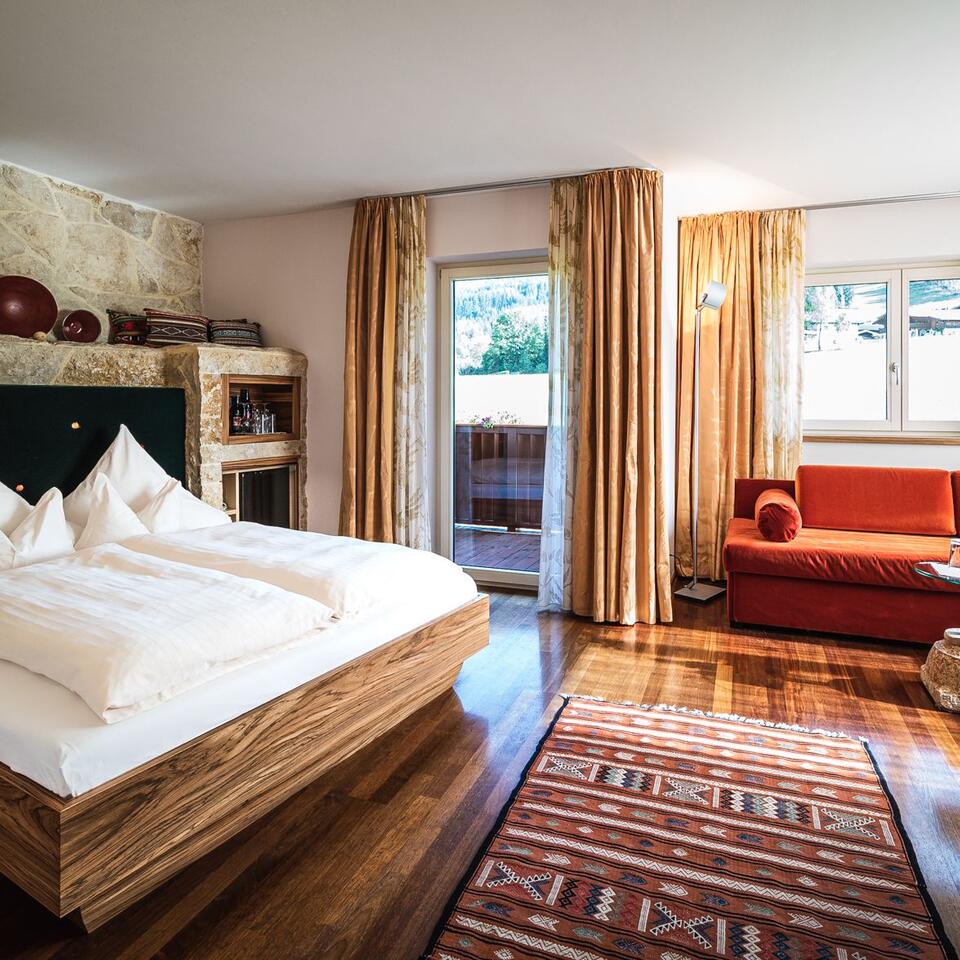 Helles Schlafzimmer mit Doppelbett, Sofa, Teppich und Balkon