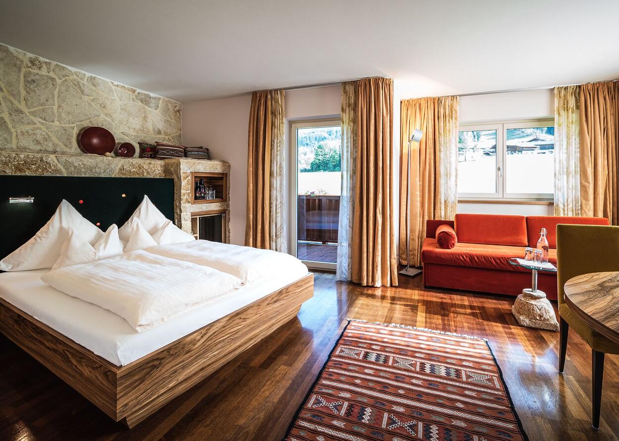 Helles Schlafzimmer mit Doppelbett, Sofa, Teppich und Balkon